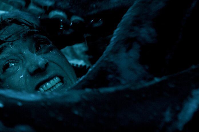 Whalefall movie still showing a terrified diver underwater in a dark blue scene, with a whale’s teeth visible behind him.