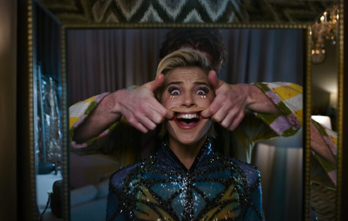 A terrified woman forces a wide smile as another person pulls at her face in a disturbing scene from the Smile horror franchise.