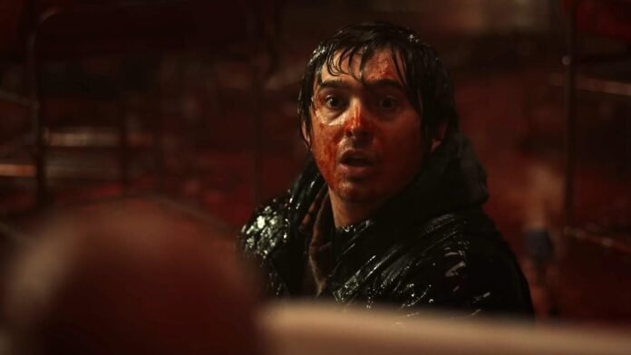 Resident Evil movie still featuring a blood-covered character in a dark setting